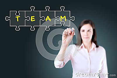 Businesswoman drawing a Teamwork Puzzle Concept on the virtual screen. Blue background.