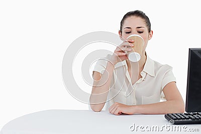 Businesswoman drinking a takeaway tea while using a computer