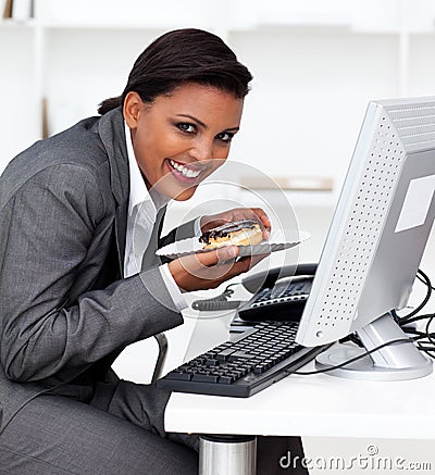 Businesswoman eating an eclair at work