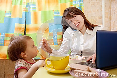 Businesswoman feeding baby and speak by mobile