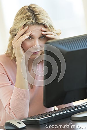 Businesswoman With Head In Hands Looking At Computer Monitor