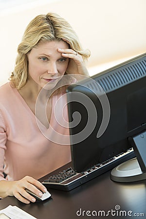 Businesswoman With Head In Hands Using Computer At Desk
