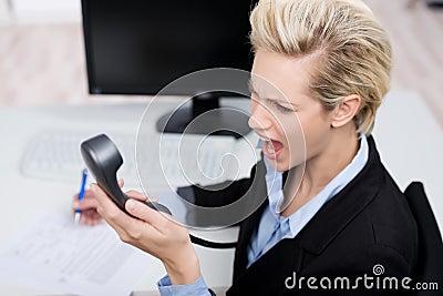 Businesswoman Shouting On Telephone Receiver At Desk