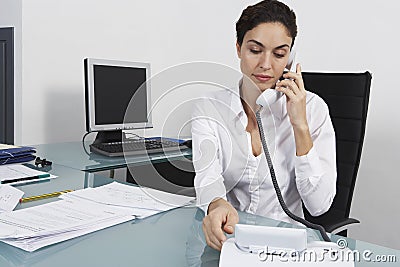 Businesswoman Using Landline Phone At Office Desk