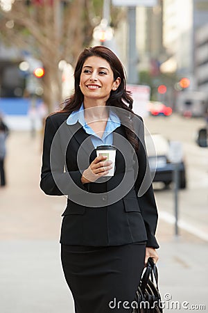 Businesswoman Walking Along Street Holding Takeaway Coffee