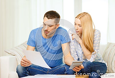 Busy couple with papers and calculator at home