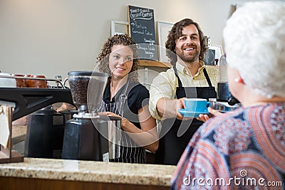 Cafe Owners Serving Coffee To Woman At Counter