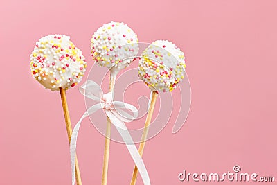 Cake pops decorated with sprinkles on pink background