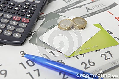 Calculator, pen, coins and credit cards on a calendar