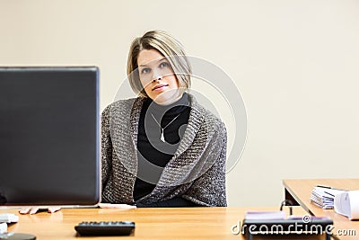 Calm young woman sittigng at desk behind pc screen