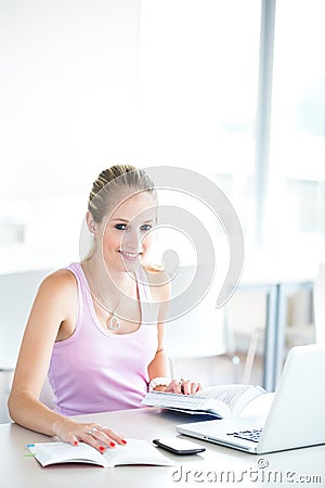 On campus - pretty, female student with books and laptop working