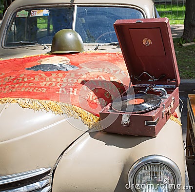 Car cowl GAZ-M-20 Pobeda with an old record player and a lying flag on show of collection Retrofest cars