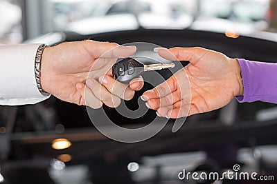 Car salesman handing over car keys in dealership