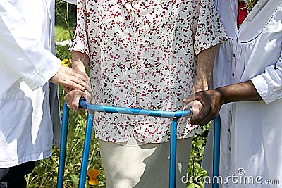 Caregivers helping a senior patient with her walker outdoor