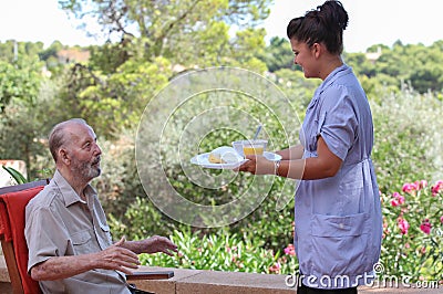 Carer giving senior food in residential home