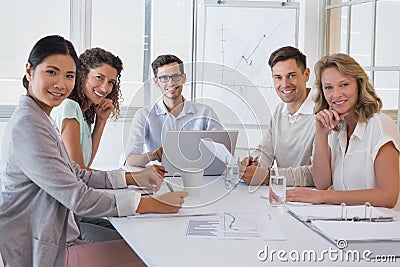 Casual business team having a meeting smiling at camera