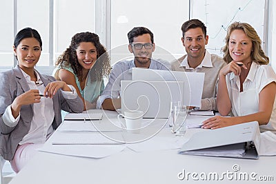 Casual business team having a meeting smiling at camera