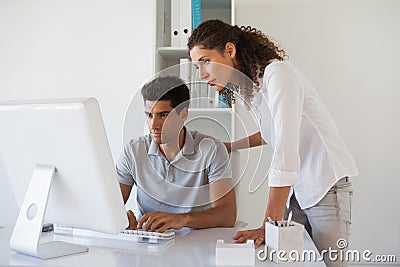 Casual business team looking at computer together at desk