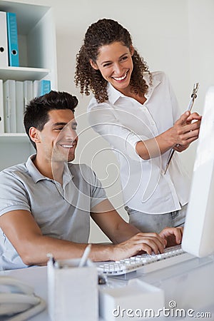 Casual business team looking at computer together at desk