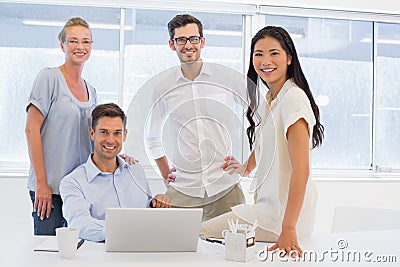 Casual business team smiling at camera at desk