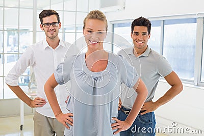 Casual business team smiling at camera with hands on hips