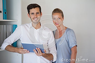 Casual business team smiling at camera man holding tablet
