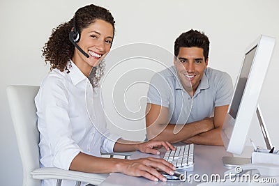 Casual business team smiling at camera together at desk