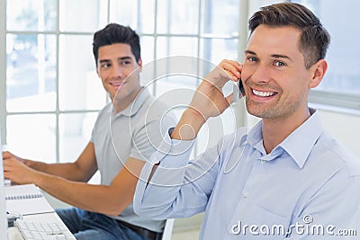 Casual businessman smiling at camera on the phone