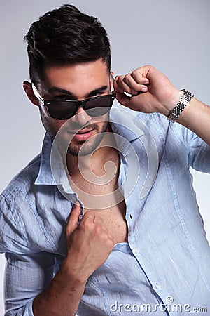 Casual man pulls down sunglasses and opens shirt