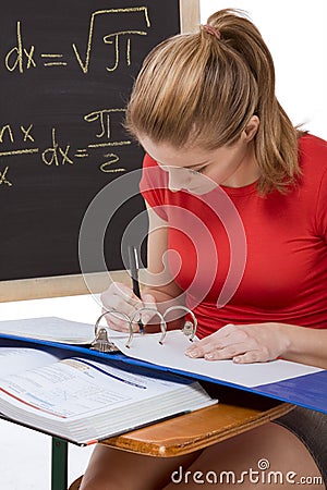 Caucasian schoolgirl by desk studying math exam