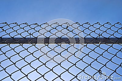 Chain link fence with bar against blue sky