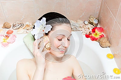 Charming young woman listening to seashell in bath