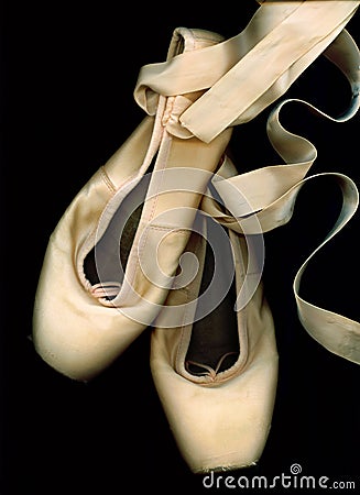 Chaussures usÃ©es de pointe de ballet sur un fond noir.