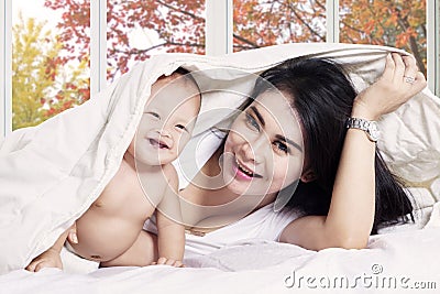 Cheerful baby under blanket with mother