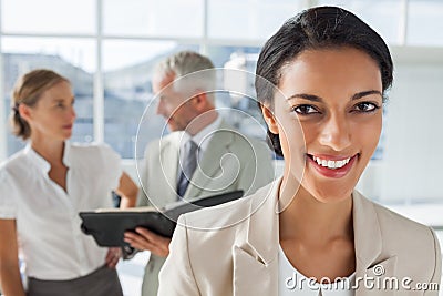 Cheerful businesswoman in front of colleagues working behind