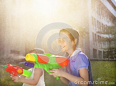 Cheerful girls playing water guns in the park