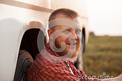 Cheerful man sitting near the car