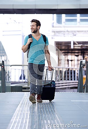 Cheerful man walking with bags at train station