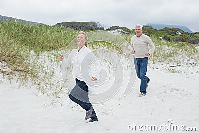 Cheerful senior couple running at beach