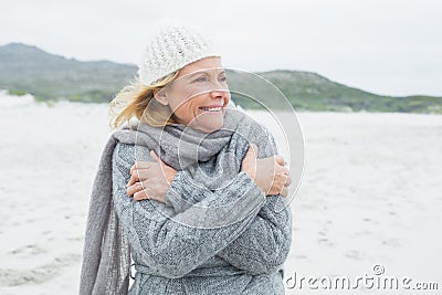 Cheerful senior woman shivering at beach