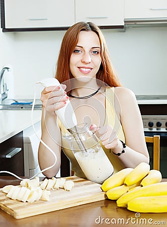 Cheerful woman making milk shake with bananas