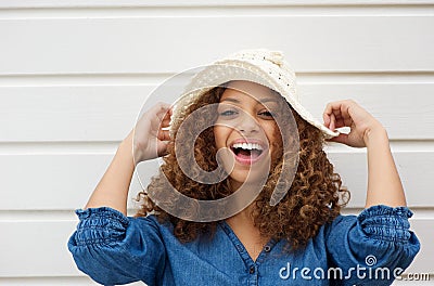 Cheerful young woman with hat laughing outdoors