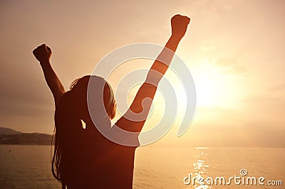 Cheering woman open arms to sunrise at sea