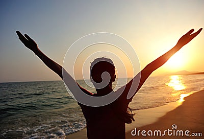 Cheering woman open arms to sunrise at sea