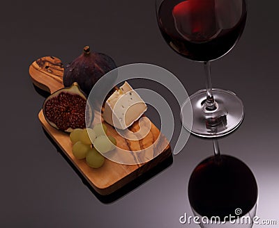Cheese, figs and grapes on cutting board