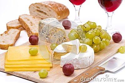 Cheese platter, grapes, bread and red wine on a wooden board