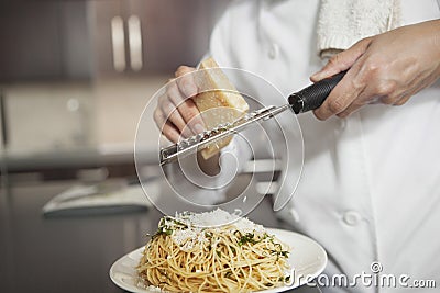 Chef Grating Cheese Onto Pasta In Kitchen