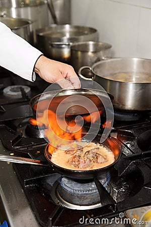 Chef is making flambe dish on restaurant kitchen