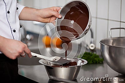 Chef Pouring Liquid Chocolate In Bowl At Kitchen Counter