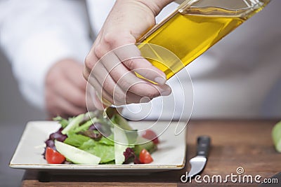 Chef Pouring Olive Oil Over Salad